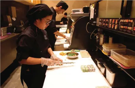  ??  ?? Chefs prepare sushi at a high-end French sushi chain that opened the previous week in northern Tehran. — AFP photos