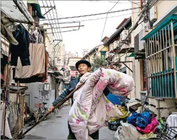  ?? CHANDAN KHANNA/AFP ?? Bao Shanchun carries a blanket outside his home in Laoximen, the city’s oldest neighbourh­ood, in Shanghai on December 26.