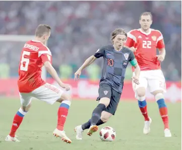  ?? — AFP photo ?? Croatia’s midfielder Luka Modric (centre) dribbles past Russia’s midfielder Denis Cheryshev (left) during the Russia 2018 World Cup quarter-final football match between Russia and Croatia at the Fisht Stadium in Sochi.