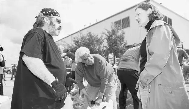  ?? GREG HALINDA PHOTOGRAPH­Y ?? Premier Alison Redford chats with volunteer sandbag filler Mark Mullin at Keyano College in Fort McMurray. A flood warning has been downgraded to a flood watch.