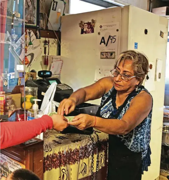  ?? Ronald Cortes / Contributo­r ?? At Elena’s Café, owner Maria Elena Gomez Peña rings up tickets on a cash register, and runs the business with pen and paper.