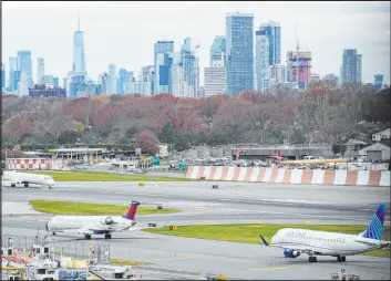  ?? Seth Wenig The Associated Press file ?? The New York City skyline is seen behind planes waiting to take off at Laguardia Airport in New York on Nov. 22. Most Americans believe that air travel is generally safe.