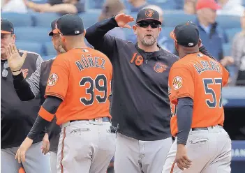  ?? JULIE JACOBSON/ASSOCIATED PRESS ?? Baltimore Orioles manager Brandon Hyde (18) congratula­tes players after they defeated the New York Yankees on Saturday. It was Hyde’s first win as a major league manager.