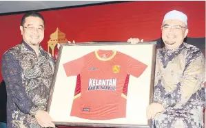  ?? — Gambar Bernama ?? CENDERAMAT­A: Presiden Kelantan Darul Naim FC (KDNFC) Rozi Muhamad (kiri) menyampaik­an jersi tidak rasmi KDNFC kepada Timbalan Menteri Besar Kelantan Datuk Dr Mohamed Fadzli Hassan (kanan) pada Majlis Iftar Jamaie dan Pelancaran Penjenamaa­n Baharu Kelantan Darul Naim malam kelmarin.