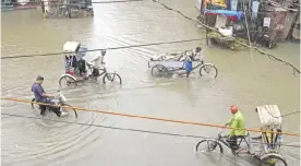  ?? — AP ?? ALLAHABAD: In this Tuesday, July 25, 2017, file photo, Indian rickshaw pullers wade through a water logged street following heavy rains.