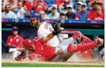  ?? RICH SCHULTZ / GETTY IMAGES ?? Cincinnati Reds catcher Curt Casali holds onto the ball after tagging out Phillies star Bryce Harper on an attempted steal of home plate during the fifth inning Sunday in Philadelph­ia. Harper was also called out at the plate in the third inning but that call was reversed after a replay review.