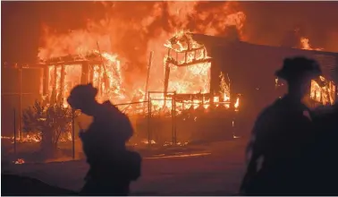  ?? NOAH BERGER/ASSOCIATED PRESS ?? Flames from a wildfire consume a residence near Oroville, Calif., on Sunday. Evening winds drove the fire through several neighborho­ods, leveling homes in its path.