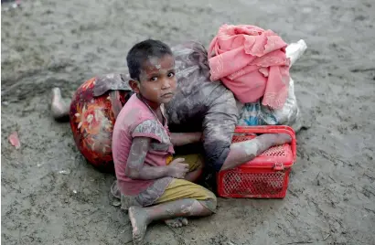  ?? Reuters ?? A Rohingya refugee girl sits next to her mother who rests after crossing the Bangladesh-Myanmar border on Wednesday. —