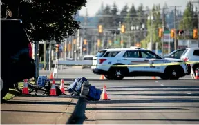  ?? AP ?? A bike and person’s belongings are seen on the sidewalk behind police tape at the scene of a shooting in Langley, British Columbia.