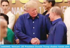  ??  ?? DANANG, Vietnam: US President Donald Trump shakes hands with Russian President Vladimir Putin as they pose for a group photo ahead of the APEC Summit leaders’ gala dinner on Friday. — AFP