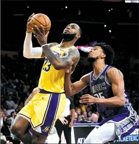  ?? AP/KELVIN KUO ?? Los Angeles Lakers forward LeBron James goes up for a shot while Sacramento Kings forward Marvin Bagley III defends during the first half of a preseason game Thursday in Los Angeles. James signed a four-year deal with the Lakers in July and made the move from the Eastern Conference, where he spent his first 15 seasons in the league.