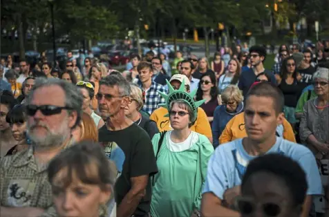  ?? Alexandra Wimley/ Post- Gazette ?? Hundreds of people, including Carolyn Gibbs of McCandless, who is dressed as the Statue of Liberty, listen to speakers during the “Lights for Liberty” vigil, held Friday in Schenley Plaza in Oakland. The vigil was intended to push Gov. Tom Wolf to close the Berks Family Residentia­l Center, which the federal government is using to detain immigrant families.