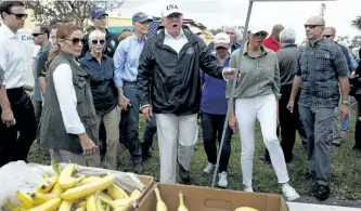  ?? EVAN VUCCI/THE ASSOCIATED PRESS ?? U.S. President Donald Trump, centre, and first lady Melania Trump, in white pants, arrive to hand out food to people impacted by hurricane Irma at Naples Estates on Thursday, in Naples, Fla.