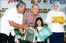  ?? — Bernama photo ?? Fadillah (centre) presents a schoolbag and the RM100 voucher to a schoolgirl. On his left is Semariang assemblywo­man Datuk Sharifah Hasidah Sayeed Aman Ghazali.