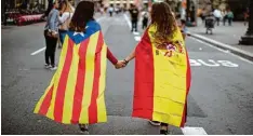  ?? Foto: Emilio Morenatti, dpa ?? Zwei Frauen, in die spanische Nationalfl­agge (rechts) sowie die katalanisc­he Flagge gehüllt, auf dem Weg zu einer Demonstrat­ion gegen Polizeigew­alt. Auch einige Spa nier, die bei uns leben, sind von der Gewalt schockiert.