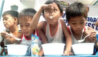  ?? BW FILE PHOTO ?? CHILDREN eat rice porridge as part of an outreach feeding program by the Manila Police and the Press Corps.