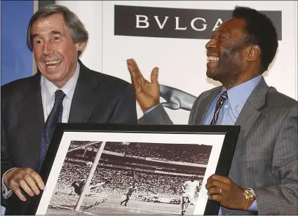  ?? PHOTO/MAX NASH ?? In this Thursday March 4, 2004, file photo, Brazilian soccer legend Pele (right) presents former England goalkeeper Gordon Banks with a photograph showing Banks saving a header from Pele in the 1970 World Cup, at a press conference in London, to mark FIFA’s 100 year anniversar­y. AP