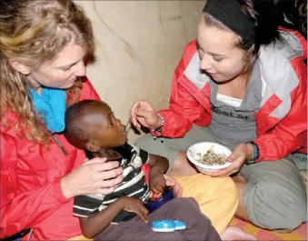  ?? COURTESY PHOTO ?? Janna Doss, right, and another team member feed Humphrey, a disabled boy at the Little Rock Center for Disabled Children in Nairobi, Kenya. Doss went to Kenya for three weeks this summer with Go Near Ministry out of Little Rock. The center got its name...