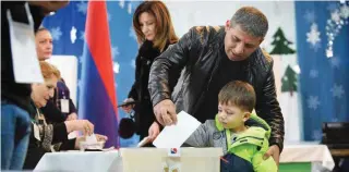  ?? - AFP ?? EXERCISING FRANCHISE: A man casts his ballot with his son as part of early parliament­ary elections in Yerevan on December 9, 2018.