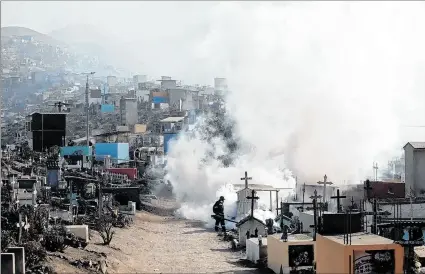  ?? EL PAÍS ?? Lima. Trabajador­es fumigan con vapor el cementerio de Nueva Esperanza, por la epidemia de dengue.