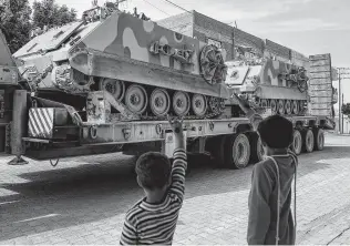  ?? Emrah Gurel / Associated Press ?? Turkish forces transport armored personnel carriers at the Syrian border Tuesday as Turkey shelled suspected Kurdish positions — a move made possible by President Donald Trump.