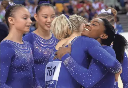  ?? FRANCOIS NEL/GETTY IMAGES ?? Simone Biles is congratula­ted by U.S. teammates after competing in the balance beam qualificat­ion Saturday, one day after going to a hospital and learning she had a kidney stone.