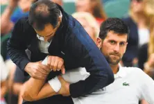  ?? Glyn Kirk / AFP / Getty Images ?? Novak Djokovic gets some medical attention on court in a break between games against Adrian Mannarino.