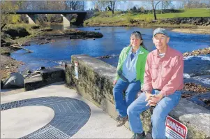  ?? KELLY LAFFERTY GERBER/KOKOMO TRIBUNE ?? Melinda and Jerry Sweeten sit on top of the fish ladder that was installed at Stockdale Mill along the Eel River in Roann, Ind.The device allows fish to swim up or down stream past the dam.