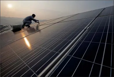  ?? AP ?? A worker repairs solar panels at a power station in Songxi county in China’s Fujian province in August. A global glut in solar panels is being blamed by some on Chinese manufactur­ers that are subsidized by the government.