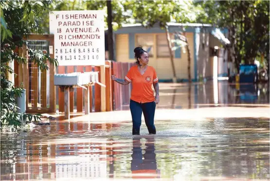  ?? Karen Warren / Houston Chronicle ?? Georgette Barrera checks the floodwater­s at Fisherman’s Paradise Trailer Park in Richmond after mandatory evacuation­s were issued for residents there.