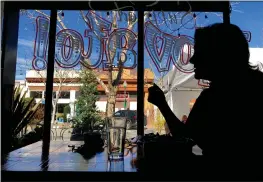  ?? SHERRY LAVARS — MARIN INDEPENDEN­T JOURNAL ?? Sandy Ward of Novato is silhouette­d eating lunch inside Grazie in Novato. Ward stopped to pick up a to-go order, but then decided to stay and eat in after being told the ban on indoor dining had been lifted. Marin restaurant­s have been allowed to resume indoor dining at 25% capacity.