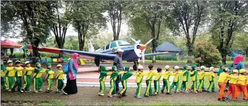  ?? BOY SLAMET/JAWA POS ?? BERMAIN DAN BELAJAR: Anak-anak TK Aisyiah Karang Pilang Surabaya berbaris rapi dengan latar belakang pesawat latih jenis Bonanza untuk menuju tempat bermain flying fox di Rumah Pintar Juanda Cendekia kemarin. Kamis menjadi hari yang paling ramai....