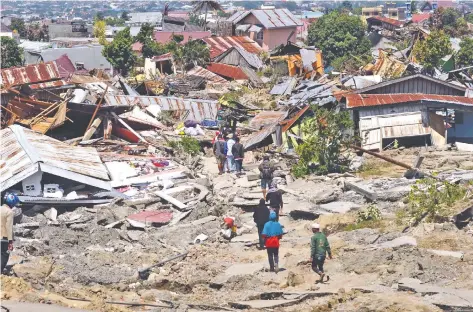  ??  ?? Residentes de Palu, Indonesia, regresaron a sus casas derrumbada­s para salvar sus pertenenci­as después de que un terremoto y un tsunami azotaran el área.