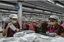  ?? Adam Dean / New York Times ?? Workers make masks at a lingerie factory in Bangkok. After months of hand-wringing, WHO endorsed use of face masks.