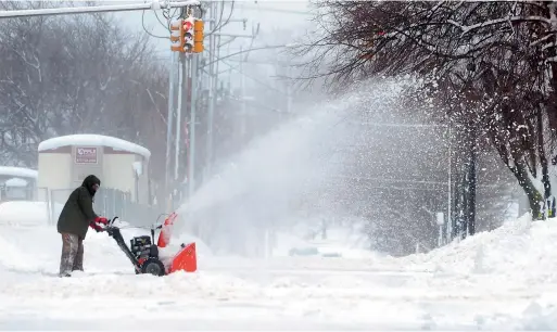  ?? — AP ?? A man clears snow in Erie, Pennsylvan­ia. The weather service office in Cleveland says a storm has brought 34 inches of snow, an all-time daily snowfall record for Erie.