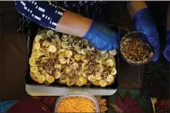  ?? ELAINE THOMPSON ?? Olga Garcia prepares capirotada, a bread pudding layered with cheese, bananas, raisins, cinnamon and pecans, as she works on an afternoon family meal Wednesday, Nov. 4, 2020, in her home in Sedro- Woolley, Wash. On any other Thanksgivi­ng, dozens of Olga’s family members would squeeze into her home for the holiday. But this year, she’ll deliver food to family spread along 30miles of the North Cascades Highway in Washington state. If the plan works, everyone will sit down to eat in their own homes at precisely 6: 30p. m. and join a group phone call.