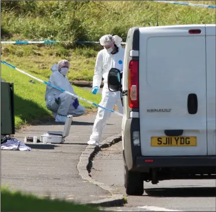  ??  ?? Forensic officers at the scene after the incident. Below, friends left floral tributes to the victim