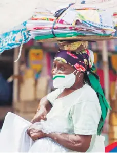  ?? AP ?? Vendedora callejera con su mascarilla, ofrece sus productos en una calle de Puerto Príncipe.