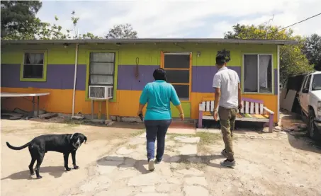  ?? Eric Gay / Associated Press ?? Eva Carranza (center), who earns $350 a month, enters her home with her friend Josue Ramirez in a colonia near Alamo, Texas.