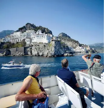  ??  ?? A bordo di un’imbarcazio­ne i turisti si godono la vista di Amalfi e della costiera