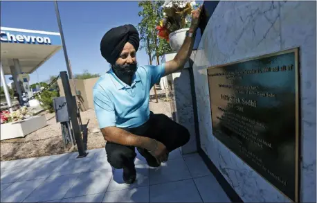  ?? ROSS D. FRANKLIN — THE ASSOCIATED PRESS FILE ?? In this file photo, Indian Sikh immigrant Rana Singh Sodhi kneels next to a memorial in Mesa, Ariz., for his murdered brother, Balbir Singh Sodhi, who was gunned down at the site four days after the attacks by a man who mistook him for a Muslim because of his turban and beard. Sodhi has preached a message of peace and tolerance in hopes of helping others better understand his religion, the fifth largest in the world with some 25 million adherents including a half-million in the United States.