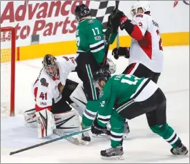  ??  ?? Ottawa Senators goalie Craig Anderson keeps his eyes on an airborne puck as Radek Faksa of the Dallas Stars closes in during third period NHL action Wednesday in Dallas. Ottawa won 5-2 to move within four points of Atlantic-Division leading Montreal.