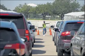  ?? Go Nakamura / Getty Images ?? An election worker guides voters in cars at a drive-thru mail ballot drop-off site at NRG Stadium on Wednesday in Houston. Gov. Gregg Abbott issued an executive order limiting each county to one mail ballot drop-off site due to the pandemic.