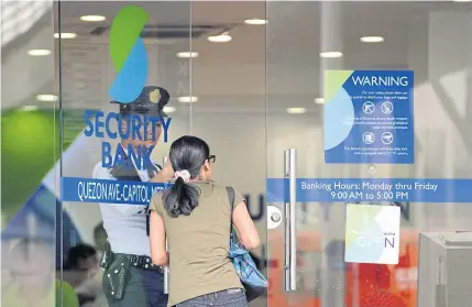  ?? AFP ?? A customer enters a branch of Security Bank in Manila yesterday.