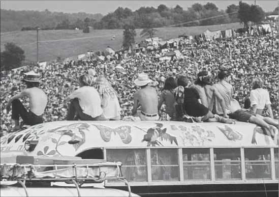  ?? Archive Photos / Getty Images ?? A WILDLY PAINTED bus was the perfect perch at Woodstock in 1969. Half a million people showed up for what turned out to be a defining boomer generation event.