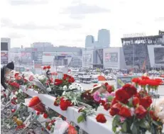  ?? — Reuters ?? A woman lays flowers on the roadside near the Crocus Hall, Moscow.