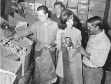  ??  ?? Joe Fenley, Bill Henderson and Jack Henderson, from the Houston Fire Department, help the Houston Chronicle’s Miss Classified bag toys in December 1970. Many former employees visited the Chronicle’s downtown offices before the building was sold.