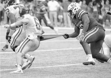  ?? GEORGE BRIDGES/ASSOCIATED PRESS FILE ?? Houston defensive tackle Ed Oliver (10) keeps a handle on Oklahoma quarterbac­k Baker Mayfield in the 2nd half of Houston’s 33-23 win over the Sooners in 2016. Oliver was the American Athletic Conference’s Rookie of the Year that season.