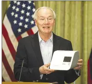  ?? (Arkansas Democrat-Gazette/Stephen Swofford) ?? Gov. Asa Hutchinson holds a quick-testing device made by Abbott during Saturday’s news conference. The machine reportedly can provide covid-19 test results in about 15 minutes.