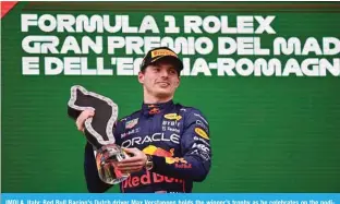  ?? — AFP ?? IMOLA, Italy: Red Bull Racing’s Dutch driver Max Verstappen holds the winner’s trophy as he celebrates on the podium after the Emilia Romagna Formula One Grand Prix at the Autodromo Internazio­nale Enzo e Dino Ferrari race track on April 24, 2022.